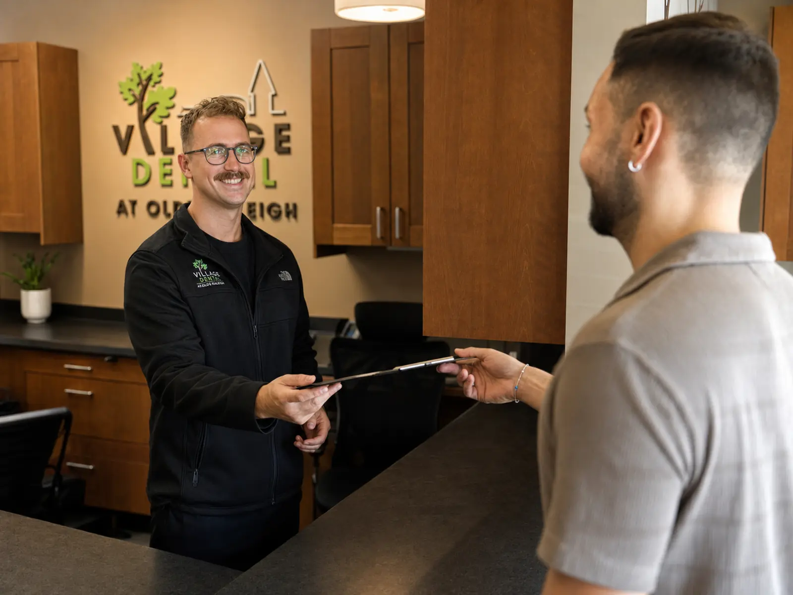 A Village Dental team member welcoming a patient at the Olde Raleigh front desk, 3101 Edwards Mill Rd, Raleigh NC